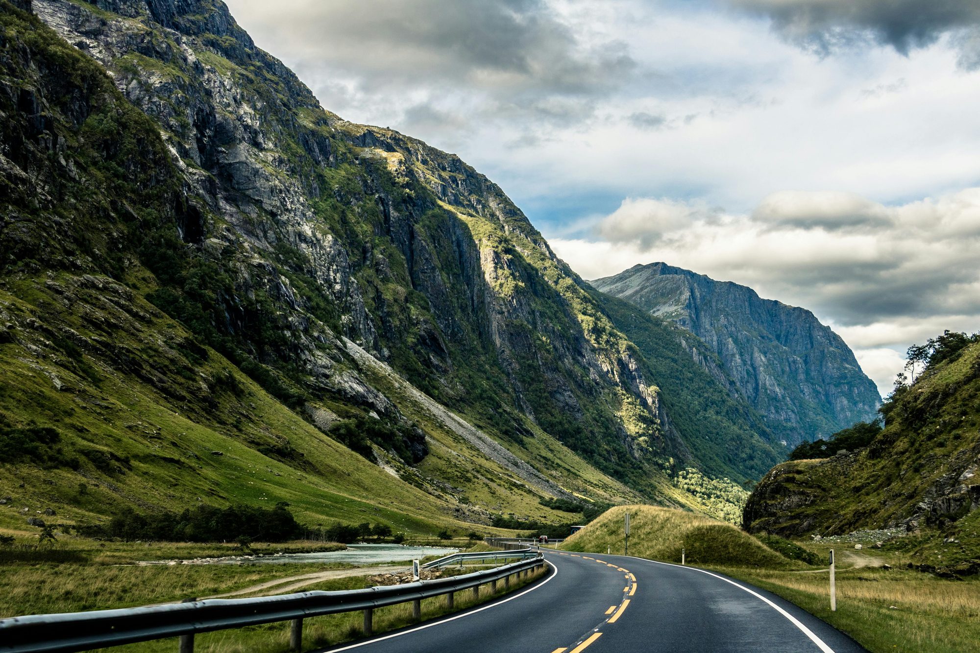 A road curving through a green mountain valley